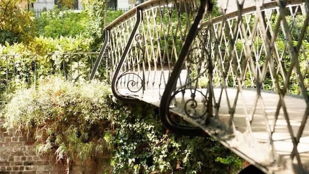 A bridge with a metal railing, surrounded by greenery and a brick wall. - Charming Savannah Townhouse Walk to Forsyth Park  Downtown (Savannah)