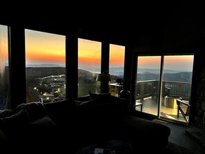 Enjoy a panoramic city view from the comfort of this room, featuring a sofa and a side table with a lamp.
