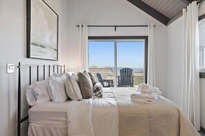 Relax in this serene space with a large bed, balcony view, and a comfortable seating area.