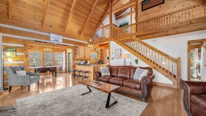 Un vaste espace de vie doté d’un haut plafond en bois, d’un escalier et d’un coin repas offrant une vue agréable.