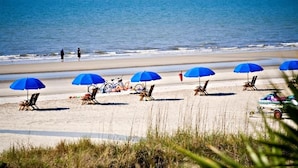 Une plage avec plusieurs parasols bleus, des chaises de plage et un jet ski.