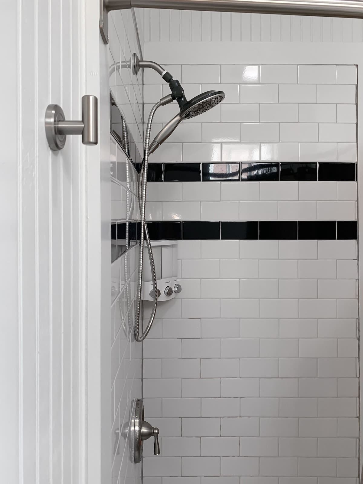 A shower with a handheld showerhead and a wall-mounted control panel.