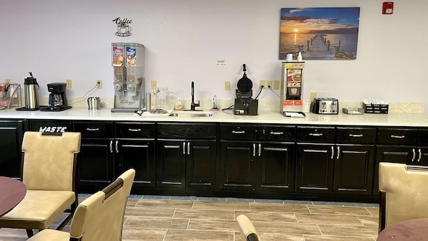 A kitchen with a coffee station, a toaster, and a painting of a sunset on the wall. - SureStay by Best Western Prince Frederick (Prince Frederick)