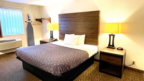 A hotel room with a large bed, two bedside tables with lamps, a window with curtains, and a wall-mounted heater. - SureStay by Best Western Prince Frederick (Prince Frederick)