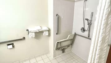 A bathroom with white tiled floors, a shower with a handheld showerhead, a grab bar, and a towel rack.