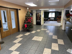 Un hall de hotel con mostrador de recepción, un árbol de Navidad y un expendedor.