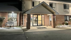 A two-story building with a brick facade, a covered entrance, and a bench outside. - SureStay by Best Western Prince Frederick (Prince Frederick)