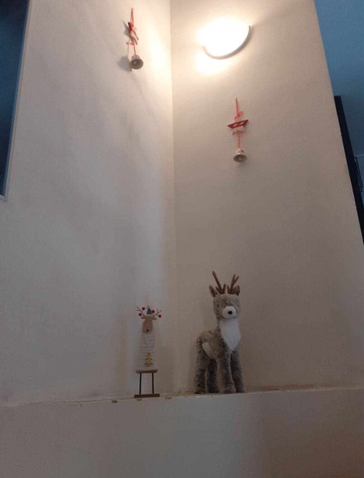 A room with a white wall, a small table with a decorative item, and a stuffed animal.