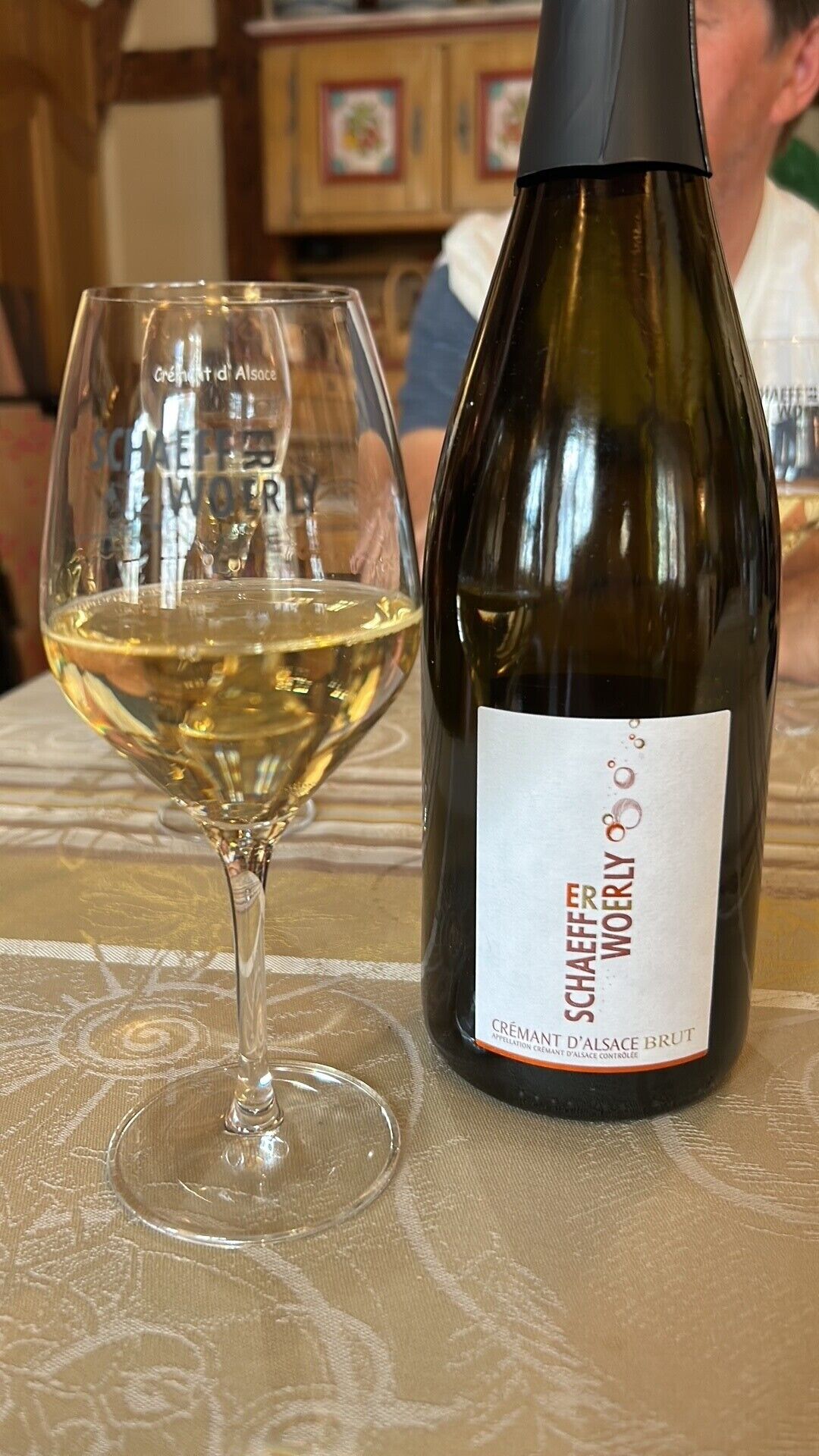 Une bouteille de vin blanc Schaeffer-Woorl et un verre du même vin, posés sur une table.