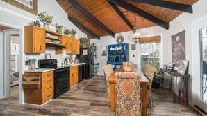 Een ruime keuken met houten kastjes, een zithoek met gestreept meubilair, en een groot raam dat voor natuurlijk licht zorgt.