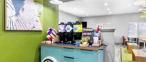 A modern cafe with a teal counter, coffee machines, and a wheelchair-accessible design.