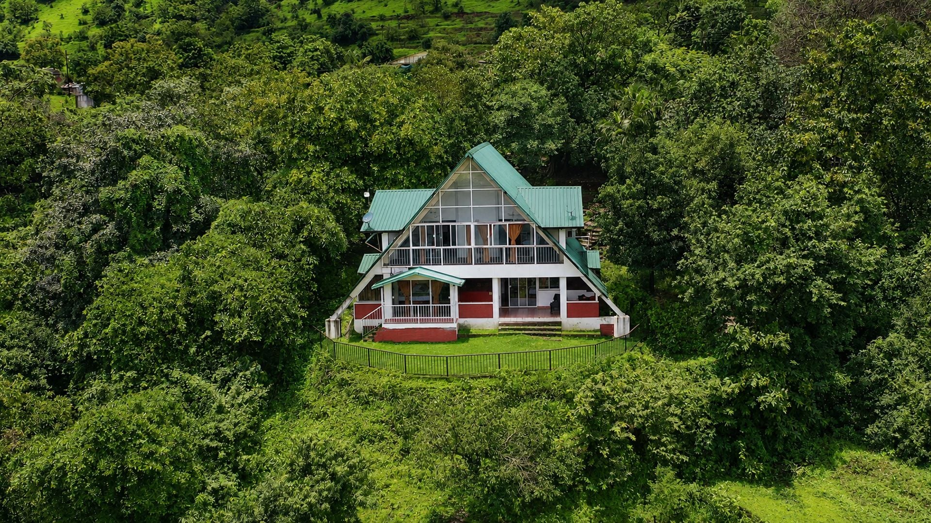 A two-story house surrounded by dense greenery.