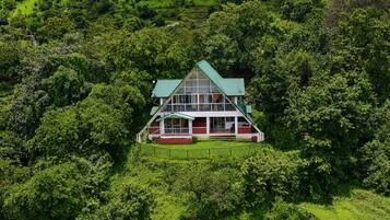 A two-story house surrounded by dense greenery.