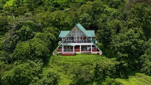 A two-story house surrounded by dense greenery. - Wind Chalet (Patan)