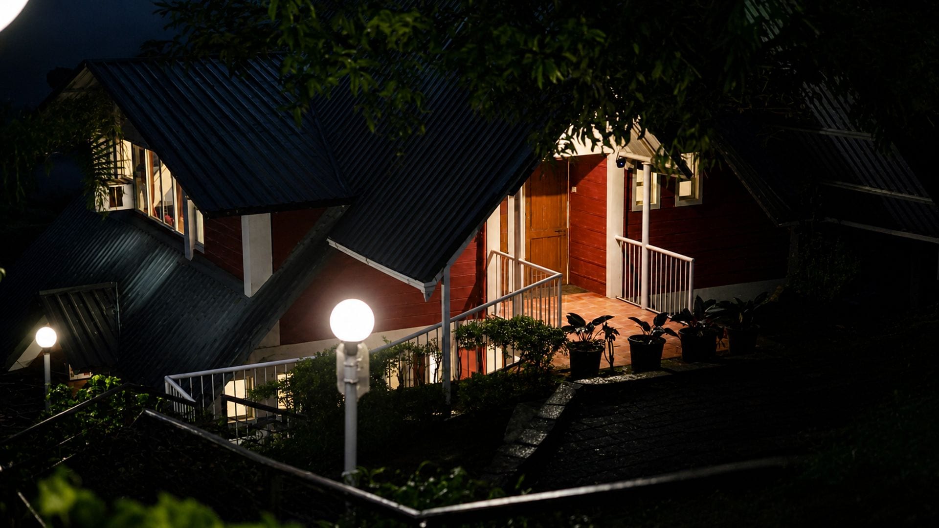 A building with a unique angular roof design, a staircase leading to a porch, and potted plants.