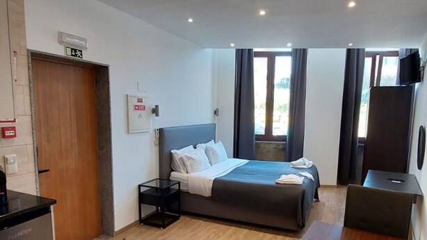 A modern hotel room with a bed, bedside table, and a TV. - NEW LIFE - FUNDACAO SERRALVES STUDIO-0F (Porto)