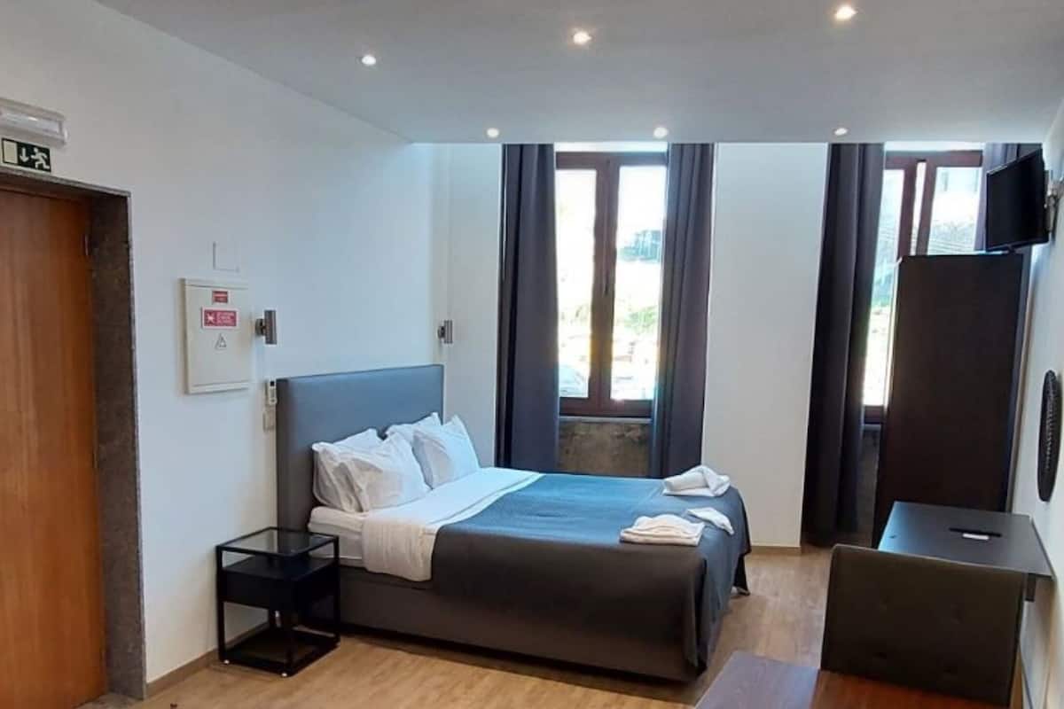 Ein modernes Hotelzimmer mit Bett, Nachttisch und Fernseher.