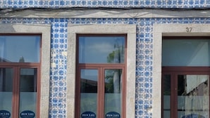 A building with blue and white patterned tiles, multiple windows with brown frames, and a visible door with a sign. - NEW LIFE - FUNDACAO SERRALVES STUDIO-0F (Porto)
