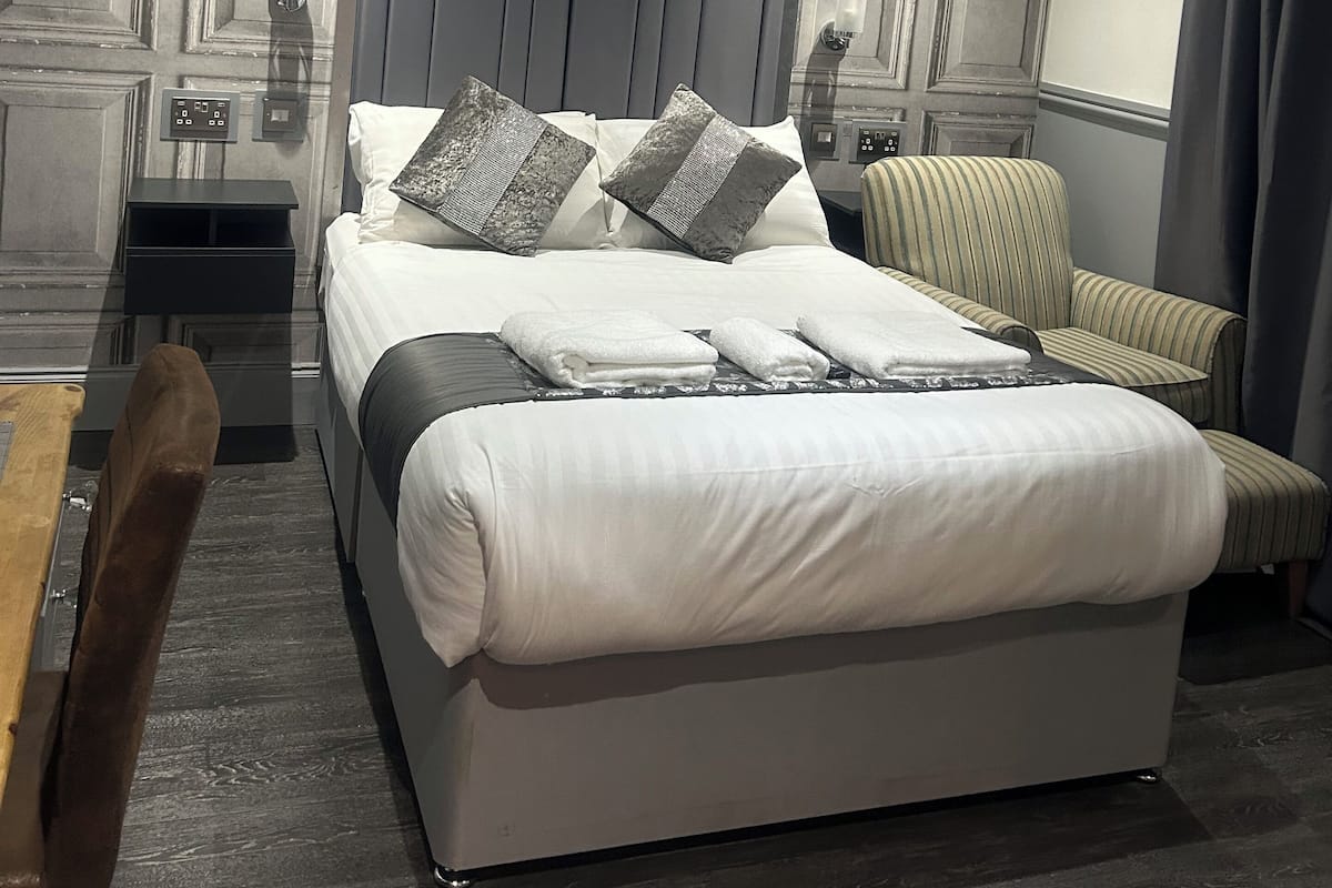 A modern bedroom with a large bed, a nightstand, a chair, and a desk.