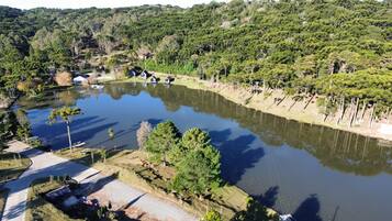 Un lac entouré d’arbres et de quelques bâtiments, avec une route qui mène à l’eau.