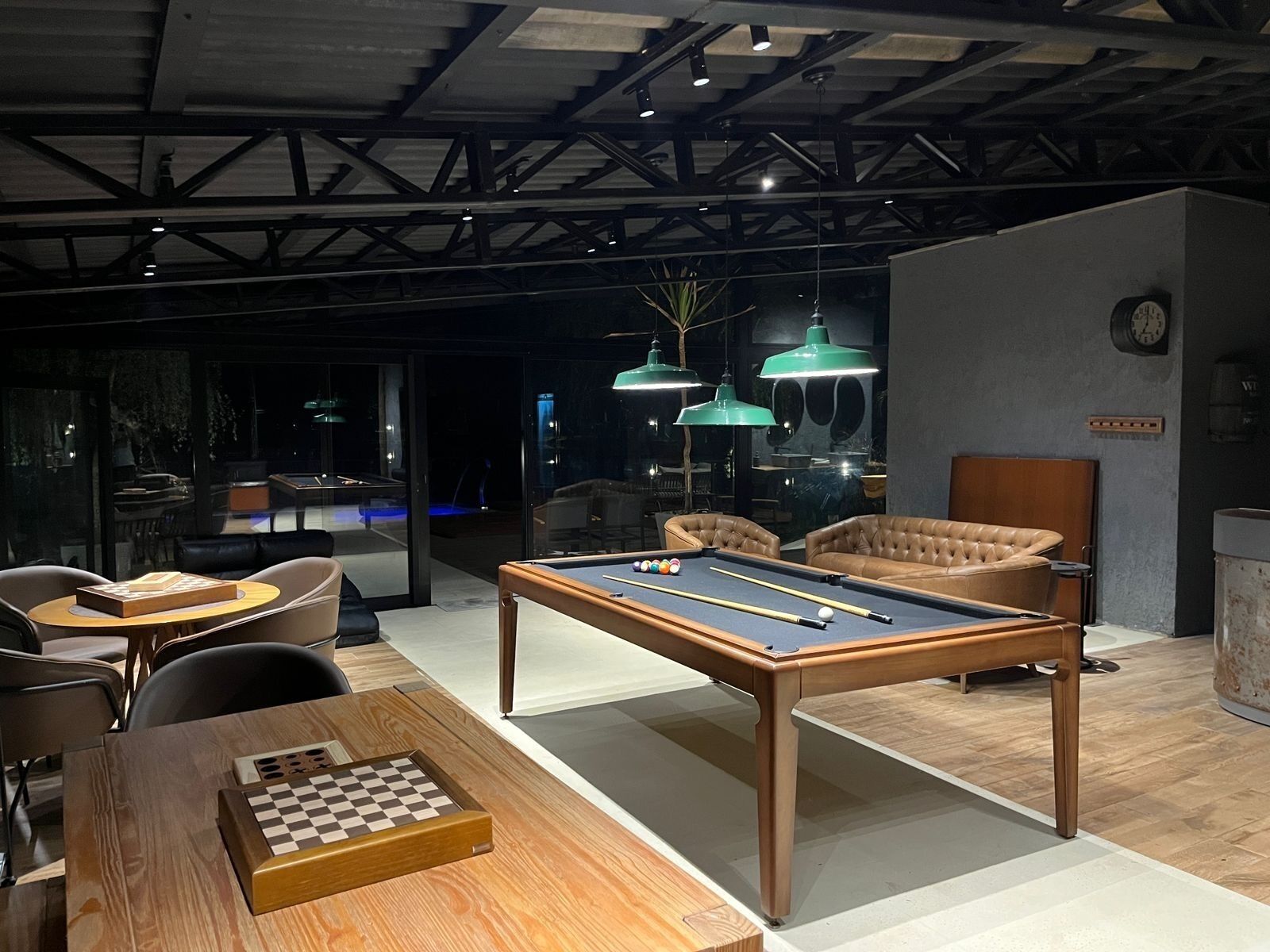 Un salón moderno con mesa de billar, sillones de cuero y una mesa de ajedrez.