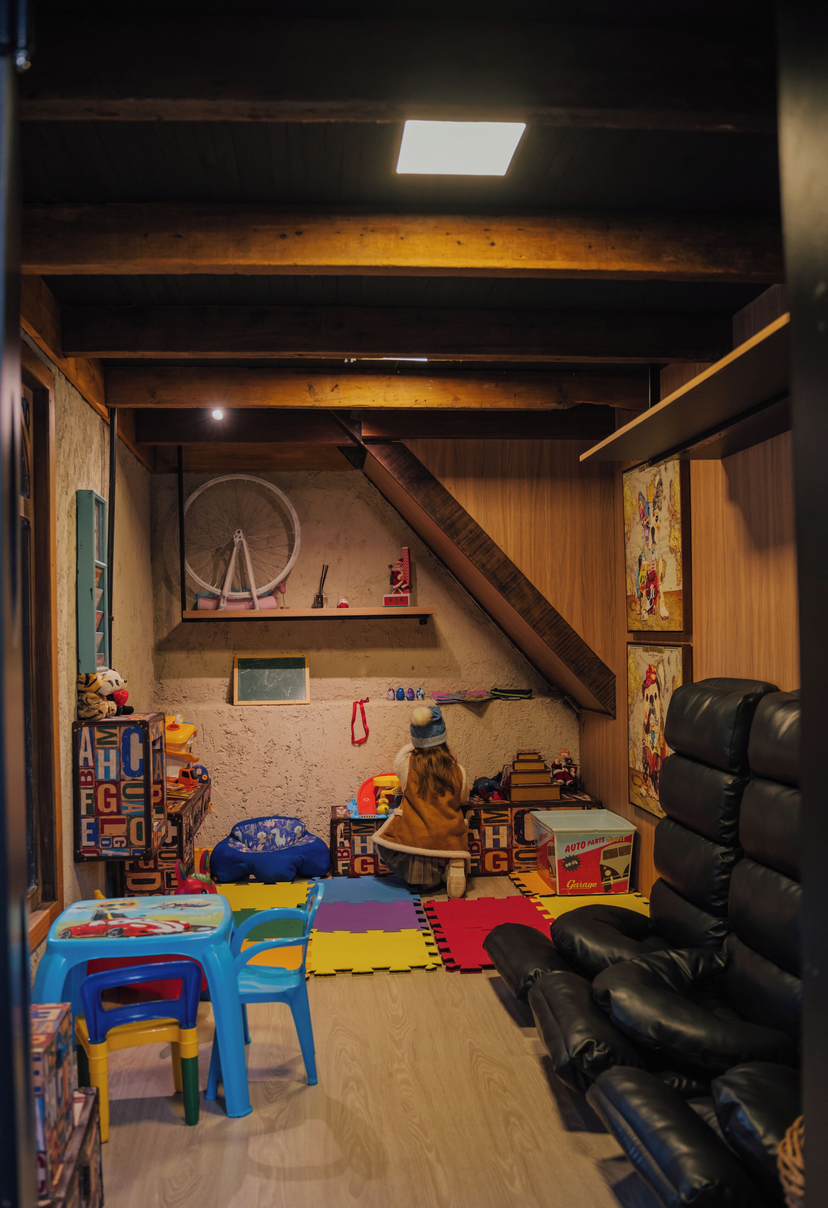 A cozy room with a wooden ceiling, a large wheel, and a black leather couch.