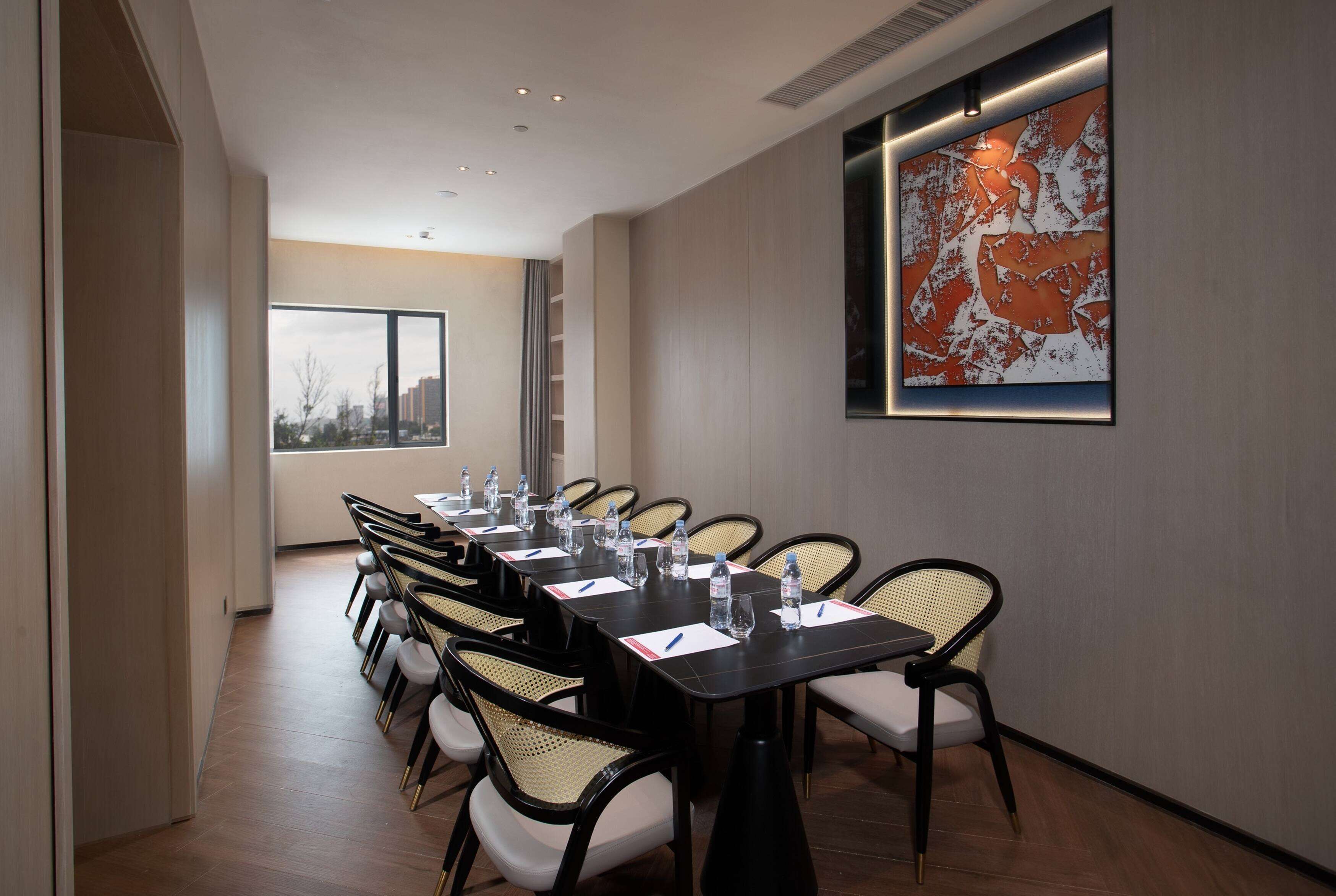 A conference room with a long table, chairs, and a large abstract painting on the wall.