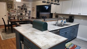 A modern kitchen with a central island, white cabinetry, and a built-in dishwasher. - A Stylish 2+ Bedroom Rancher (Clifton Forge)