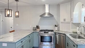 A kitchen with light blue cabinets, a stainless steel range hood, and a wooden floor. - Lake Greenwood Home -- Come refresh in a quiet cove!  (Greenwood)
