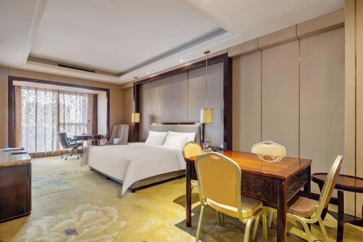 A hotel room with a bed, desk, and dining table.