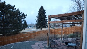 A patio area with a pergola, outdoor seating, and a wooden fence. - Pet Friendly, Mountain View Home with Park/Playground Access  *see description* (Colorado Springs)