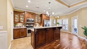 Una cocina amplia con armarios de madera, una isla central y un gran ventanal que proporciona luz natural.