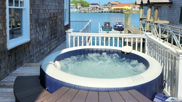 A hot tub on a wooden deck with a view of a dock and water. - The Capone House | Historic Luxury on the Bay (Atlantic City)