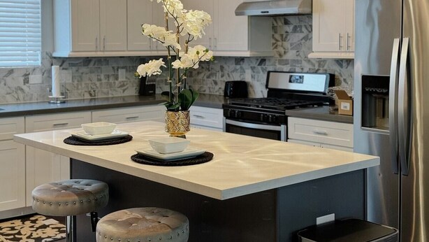 A modern kitchen with a marble countertop, stainless steel appliances, and pendant lighting. - 3-Story Downtown Houston Safe Haven (Houston)