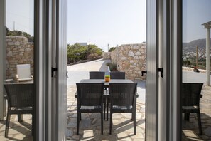 An outdoor patio with a stone wall, wicker furniture, and a view of the landscape.