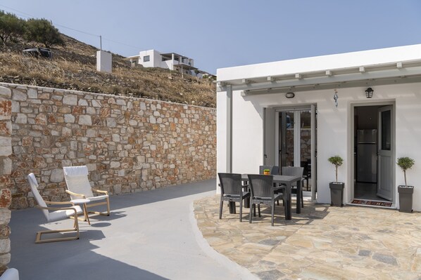 A stone wall, outdoor seating, and a modern building with a door.