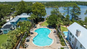 Una gran piscina rodeada de sillas de descanso y sombrillas, con vista a un lago y árboles al fondo.