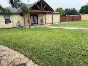 A house with a covered porch, a stone border, and a well-maintained lawn.