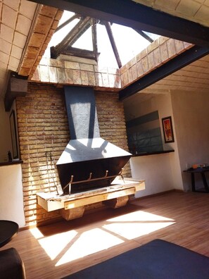 A modern kitchen with a brick wall, a large black stove, and a skylight. - Casa en el corazón de Punta del Este! (Punta del Este)