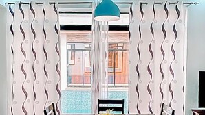 A dining area with a table and chairs, a blue pendant light, and patterned curtains. - 2 Bed/2.5 Bath Villa (Lewa) (Monrovia)