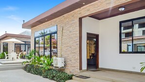 A modern building with a stone facade, large windows, and a covered outdoor seating area.