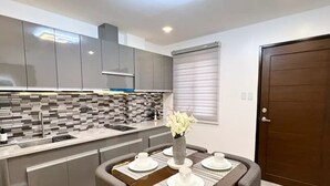 Une cuisine moderne avec des meubles gris, un pare-feu en carrelage et un coin repas avec une table dressée pour quatre personnes.