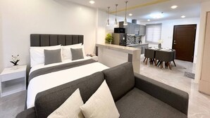 Une chambre d’hôtel moderne dotée d’un grand lit, d’un canapé, d’un coin repas et d’une cuisine.