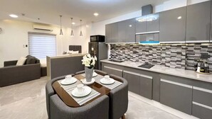 Une cuisine moderne avec des meubles gris, un pare-feu en carrelage et un coin repas avec une table dressée pour quatre personnes.