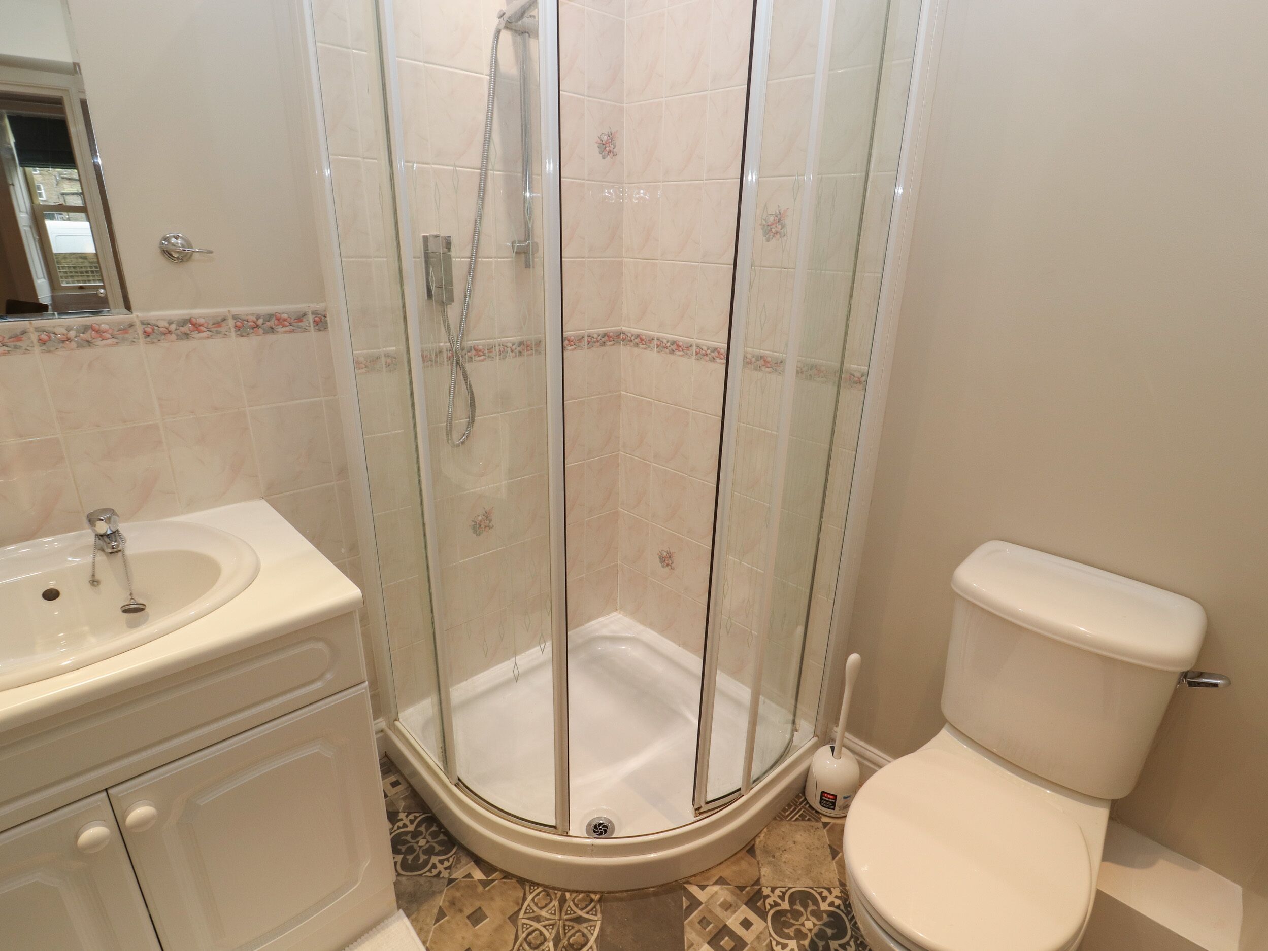 A bathroom with a glass-enclosed shower, a toilet, and a sink.