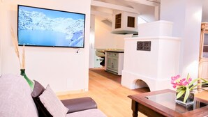 Een woonkamer met een flatscreen televisie, een bank, een salontafel en een keuken op de achtergrond.