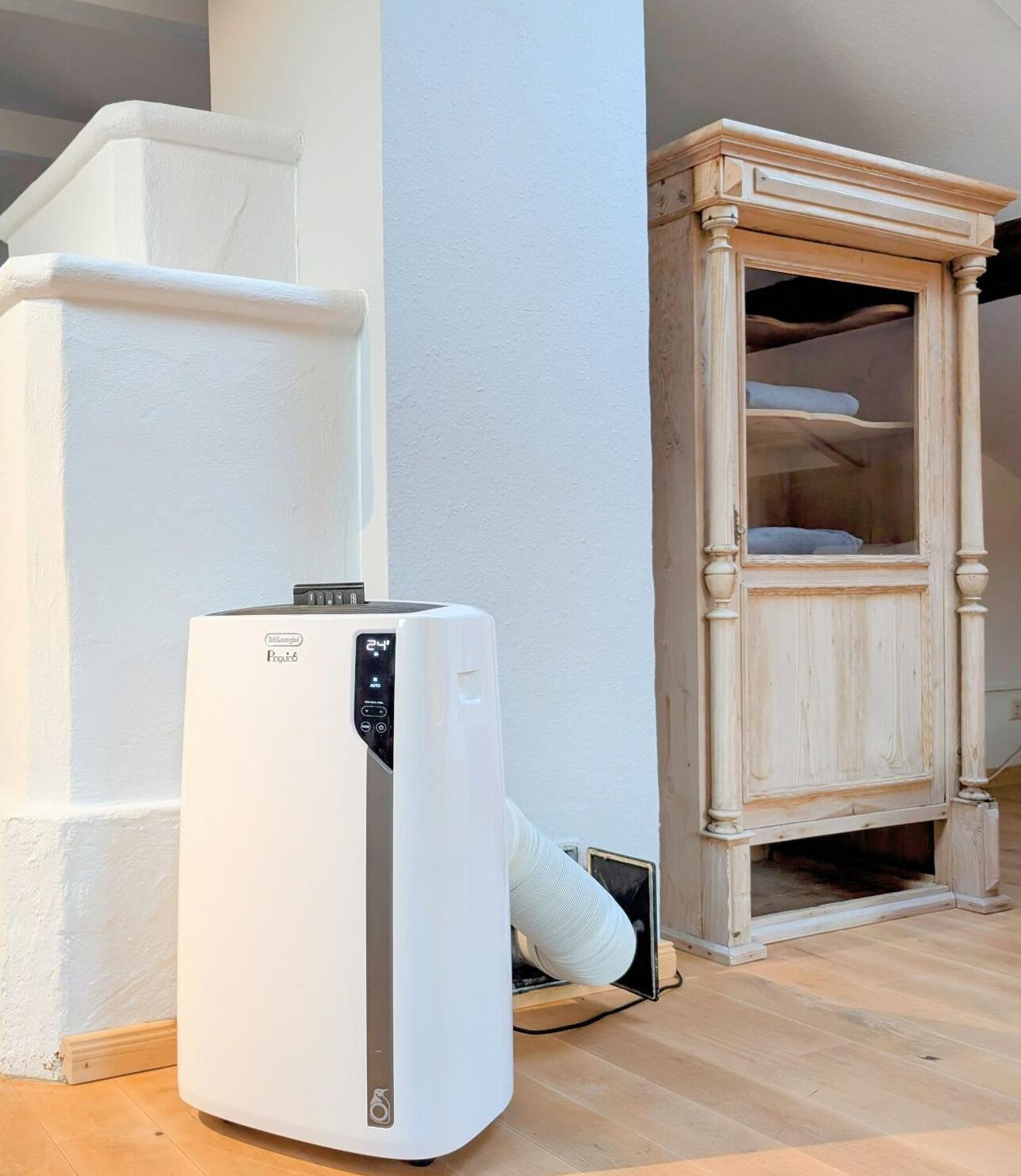 Un réfrigérateur blanc dans un coin, un meuble en bois avec des étagères et un mur blanc.