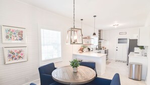Una cocina moderna con armarios blancos, una isla central e iluminación colgante.