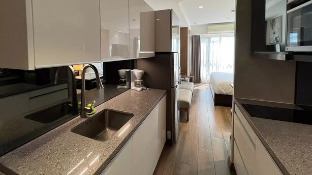 A modern kitchen with a granite countertop, stainless steel sink, and a coffee machine. - Luxury Abode Near Walking Street

 (Malabañas)