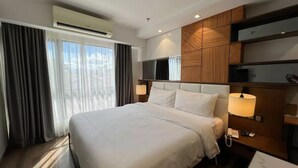 A modern hotel room with a large bed, wooden paneling, a desk, and a window with curtains. - Luxury Abode Near Walking Street

 (Malabañas)